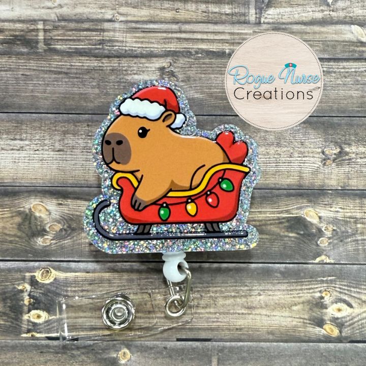 Capybara Wearing a Santa Hat, Riding Inside a holiday sleigh Retractable Badge Reel, UV Printed on Silver Glitter Acrylic