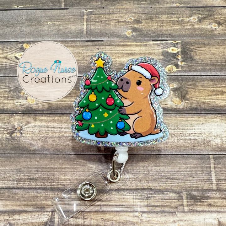 Capybara decorating a Christmas Tree Wearing a Santa Hat Retractable Badge Reel, UV Printed on Silver Glitter Acrylic